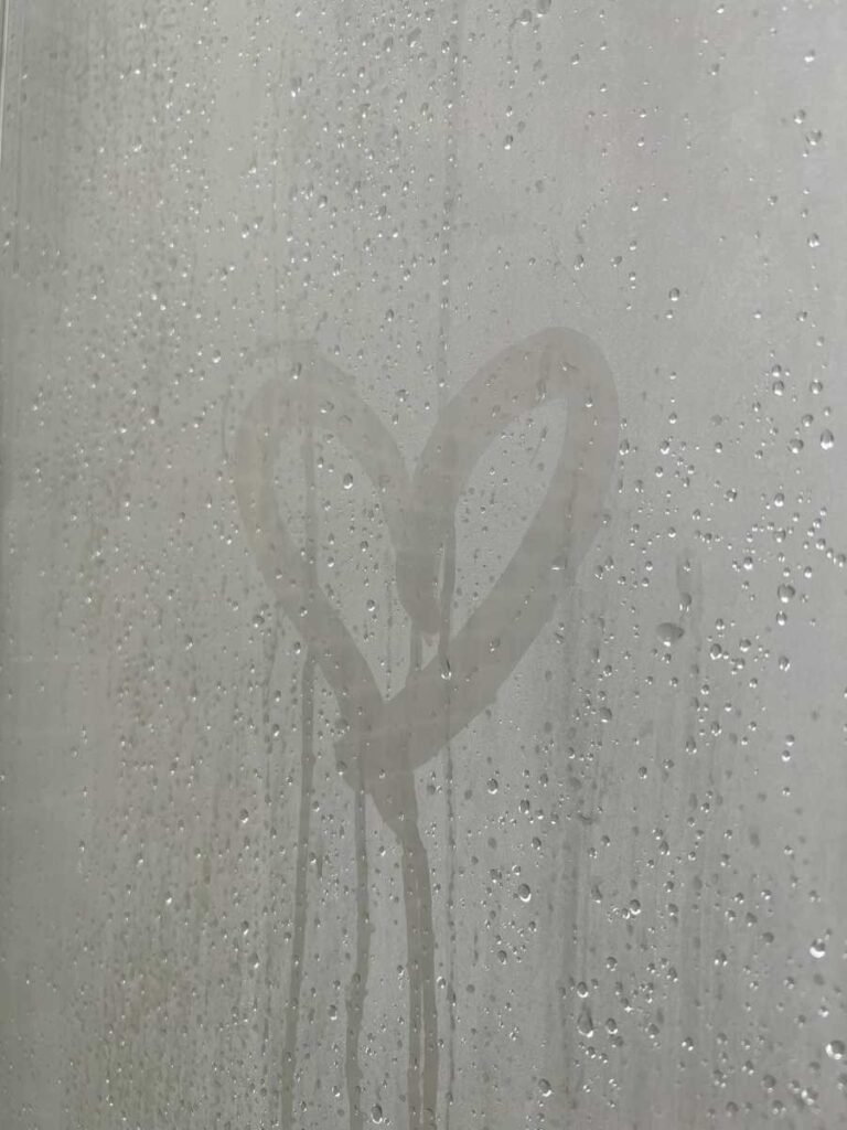 A heart drawn in the condensation on a window. This image represents the importance of managing condensation in buildings to maintain a healthy indoor environment. Proper ventilation and moisture management can prevent the buildup of condensation and promote comfort and wellbeing for building occupants.
